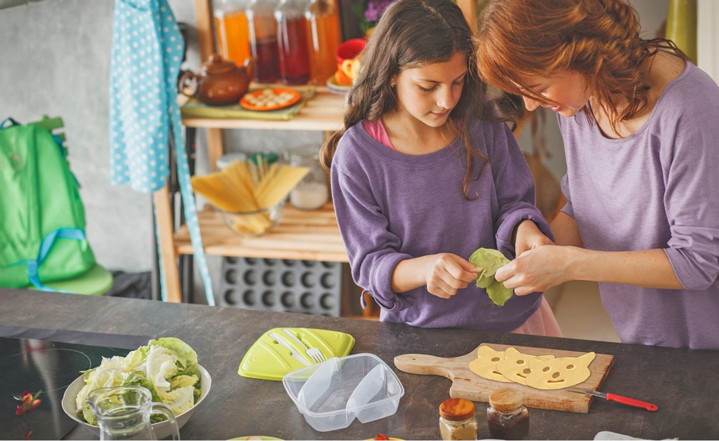 Mutter und Tochter bereiten gemeinsam Käsebrot mit Gemüse in der Küche zu